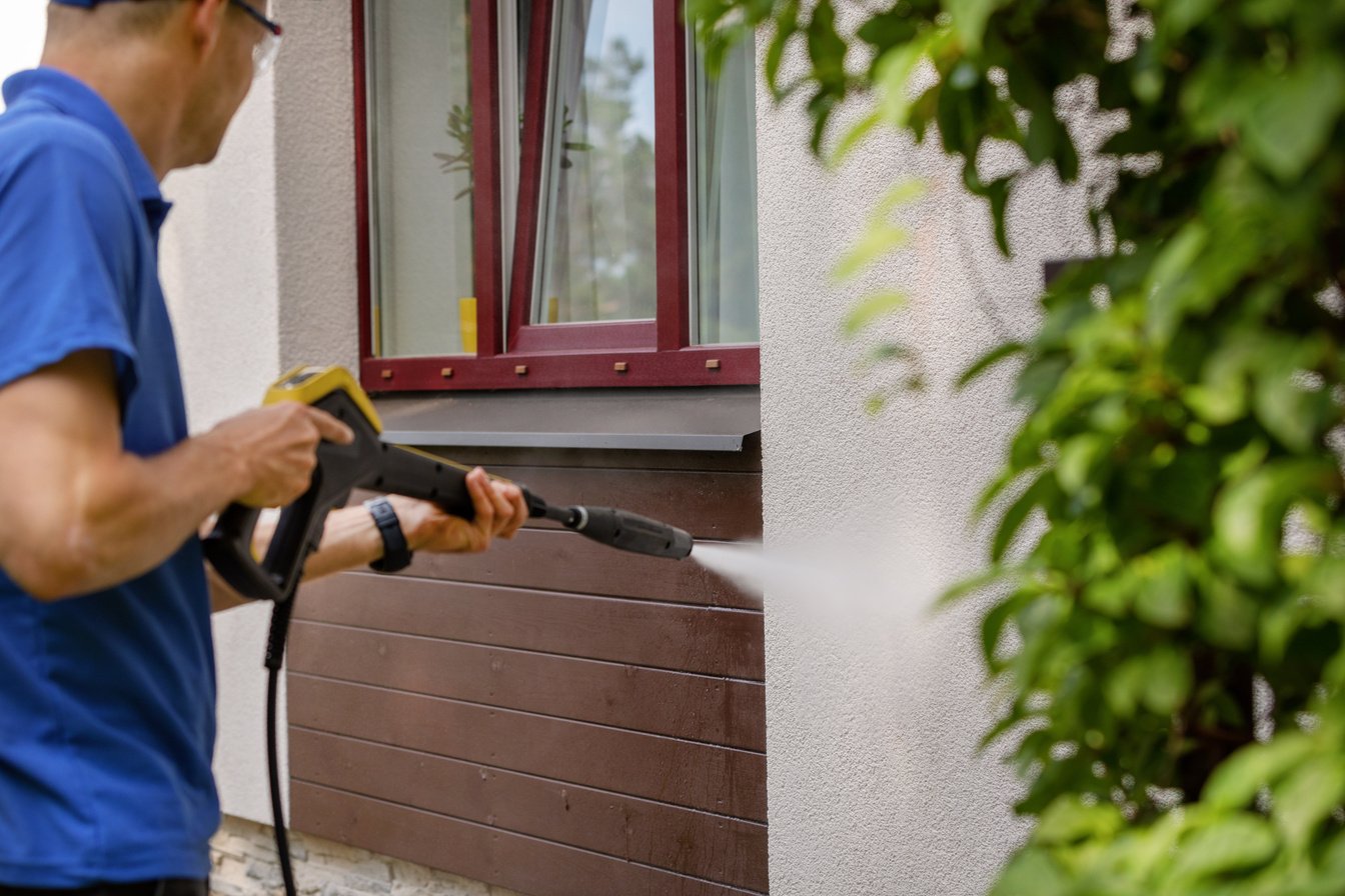 house facade cleaning service. man washing wall with high pressure washer